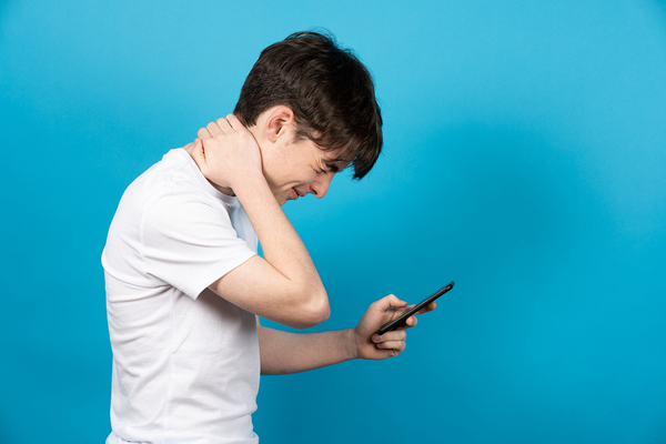 首を押さえながらスマホを操作する男性